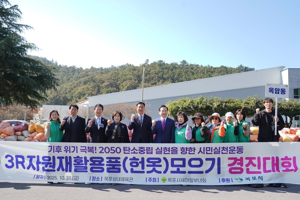 '3R 자원재활용품(헌옷) 모으기 경진대회' 현수막 뒤에서 옥암동 참가자들이 다 함께 파이팅을 외치는 모습이다. 배경의 숲과 파란 하늘 아래 행사가 진행되고 있다.