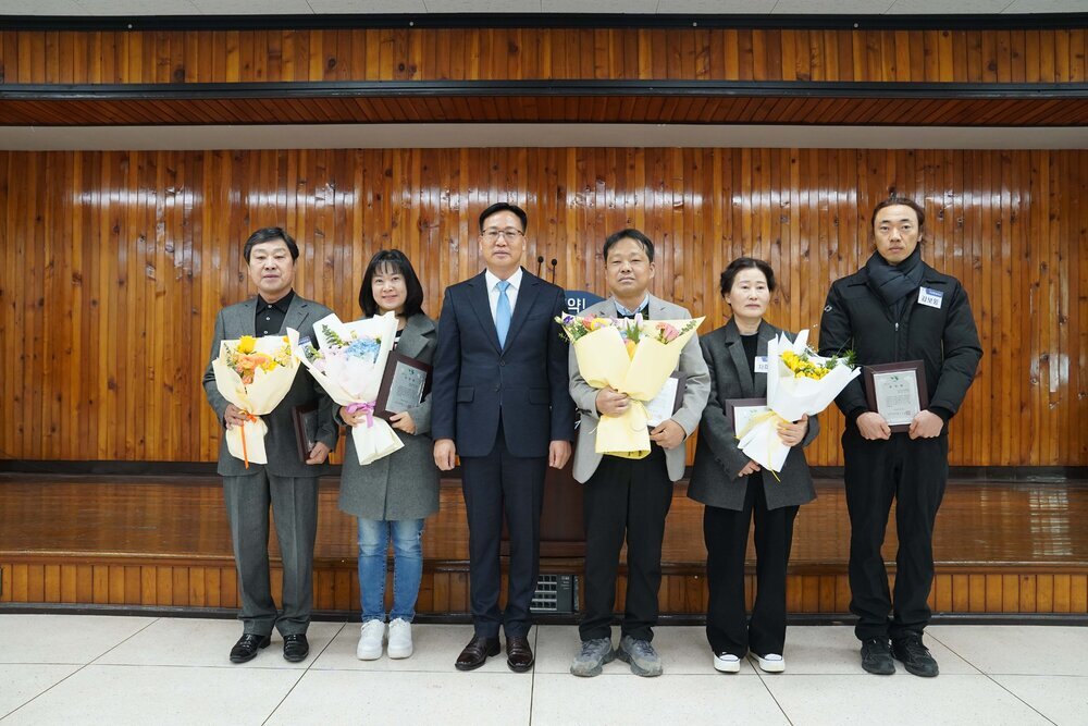 2월 정례조회 행사에서 정장을 입고 안경을 쓴 남성이 수상자들과 함께 기념촬영을 하고 있으며, 왼쪽부터 황춘호, 박성아, 이대인, 차미경, 김보잉이 꽃다발과 상패를 들고 일렬로 서 있다.