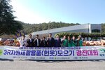 '3R 자원재활용품(헌옷) 모으기 경진대회' 현수막 뒤에서 상동 피켓을 든 참가자들이 파이팅 포즈를 취하고 있다. 쌓여있는 엄청난 양의 자원재활용품 자루들이 눈에 띈다.