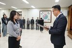 2026년 상반기 4급이하 정기인사로 정장을 입은 남성이 실내 행사장에서 한 여성에게 상장을 전달하며 내용을 읽고 있고, 여성은 회색 상의를 입고 두 손을 모은 상태로 서 있으며 뒤쪽에는 참석자들이 줄지어 서서 행사를 지켜보고 있다.
