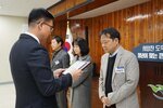 2월 정례조회에 정장을 입고 안경을 낀 남성이 밝은 오트밀색 정장 자켓을 입은 이대인에게 패를 수여하고 있다.