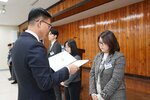 2월 정례조회에 정장을 입고 안경을 낀 남성이 목까지오는 단발머리에 흰색 티에 회색 체크무늬 자켓을 입은 강보경에게 패를 수여하고 있다.