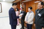 4월 정례조회에 정장을 입고 안경을 낀 남성이 밝은 베이지색 패딩을 입은 조금임에게 패를 수여하고 있다
