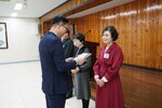 4월 정례조회에 정장을 입고 안경을 낀 남성이 와인색 원피스를 입은 이유자에게 패를 수여하고 있다