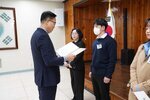 4월 정례조회에 정장을 입고 안경을 낀 남성이 짙은 네이비색 스웨터를 입은 정한결에게 패를 수여하고 있다